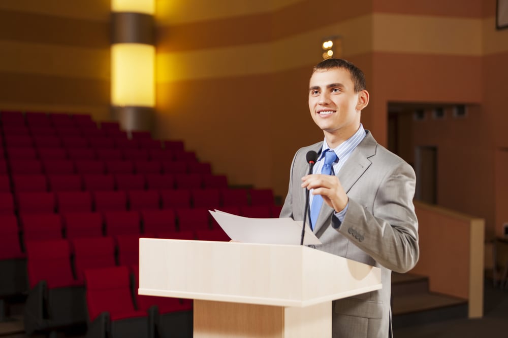 Businessman standing on stage and reporting for audience