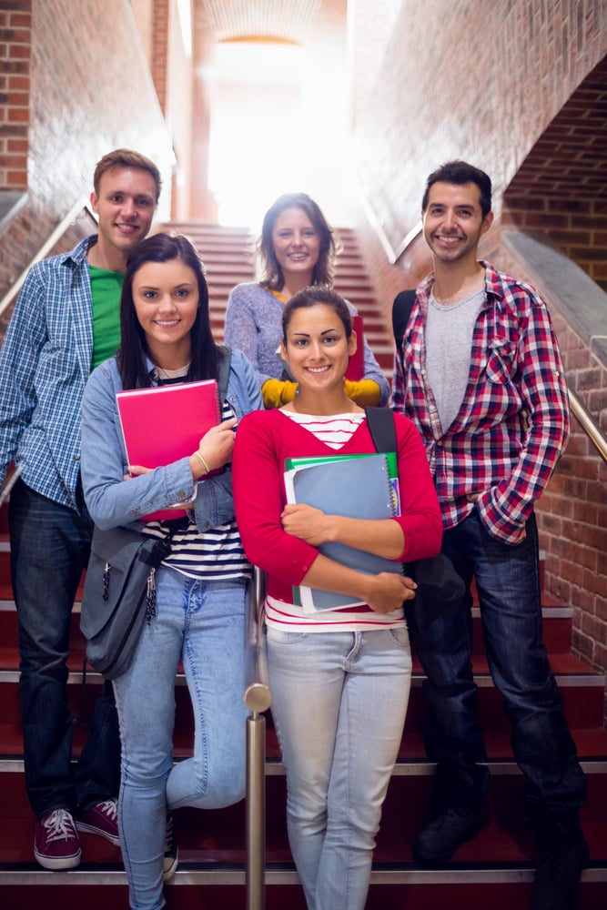 Group portrait of young college students standing on stairs in the college